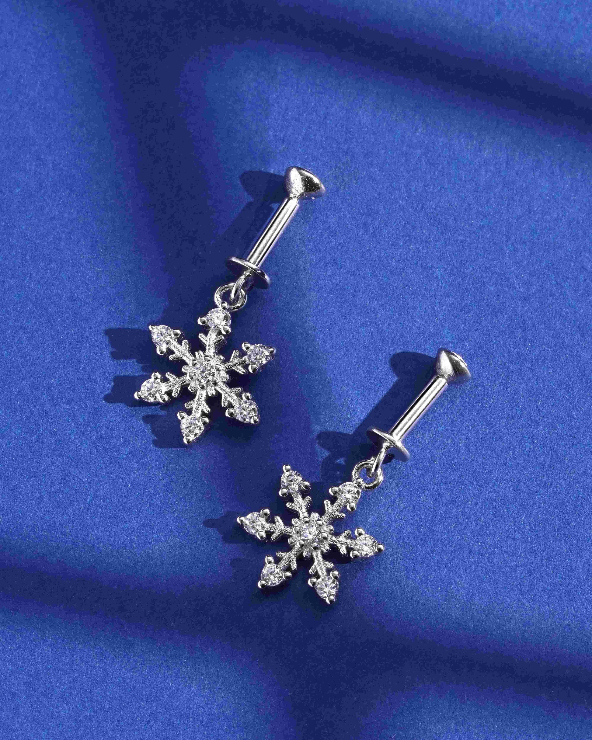 Snowflake Helix Earring - Ice on Ear shown as a pair on blue background, sterling silver screw design with hanging crystal snowflakes.