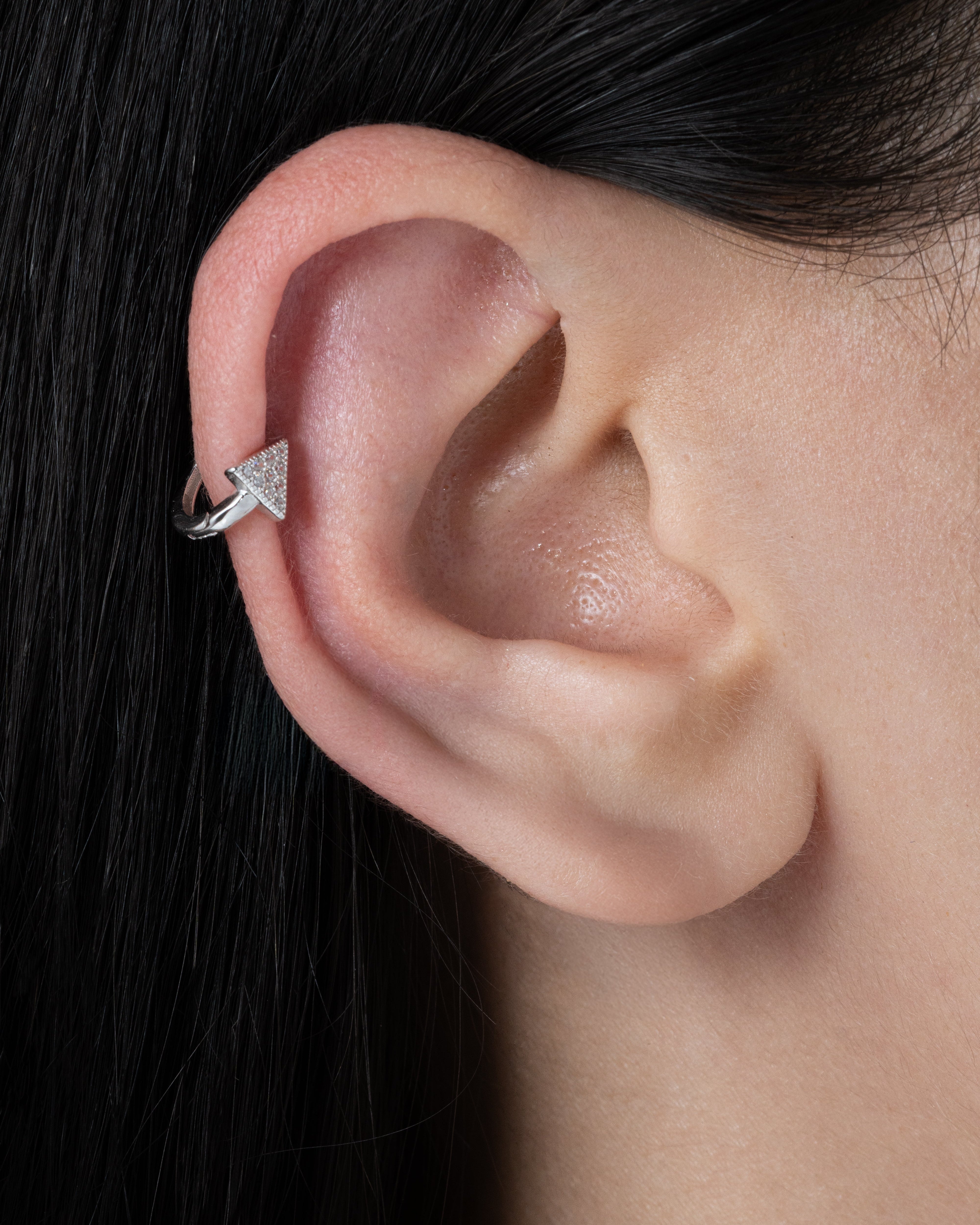 Pave' Edge Huggie Hoop in 92.5 sterling silver worn on a forward helix piercing, featuring sparkling zirconia pave stones for a minimalist look.